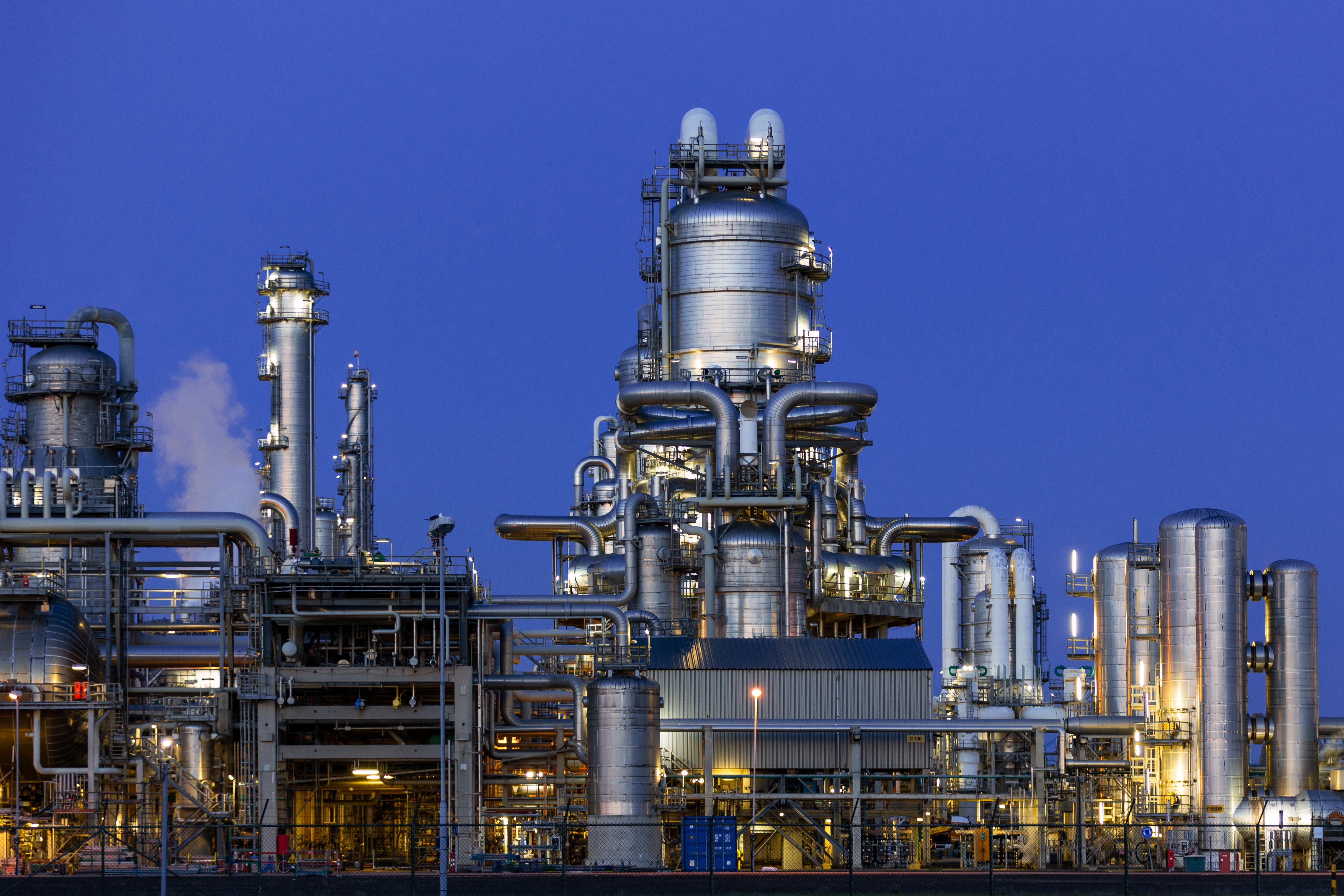 Illuminated industrial processing plant beneath a deep blue evening sky